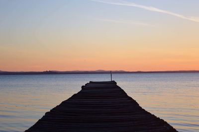 Pier over sea against sky during sunset