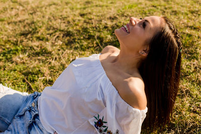 Side view of happy young woman lying on grassy field