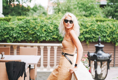 Adult elegant blonde woman in sunglasses beige clothes in summer city street cafe