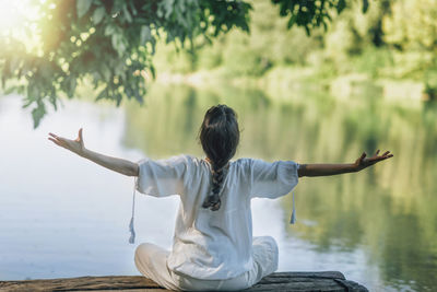 Self-discovery meditation in nature by the lake. woman sitting in lotus position meditating 