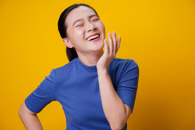 Happy boy standing against yellow background