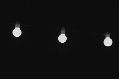 Low angle view of illuminated light bulb against clear sky