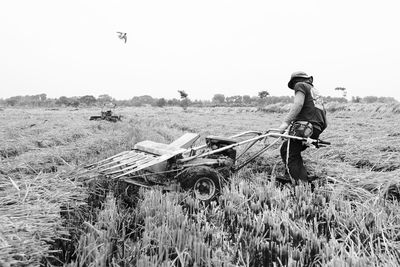Farmer with machine on field against sky