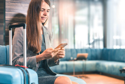 Young woman using mobile phone while sitting in bus