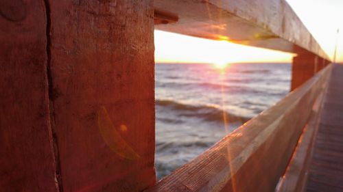 Close-up of wood against sea at sunset