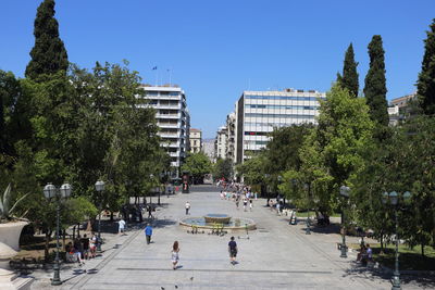 People walking on road in city against clear sky