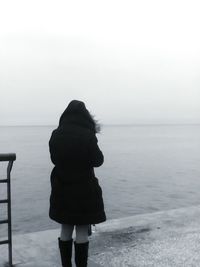 Rear view of woman standing on beach against clear sky