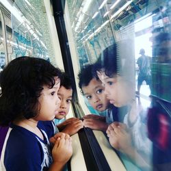 Siblings looking through window in train