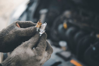 Close-up of man holding spark plug