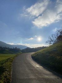 Empty road along landscape against sky