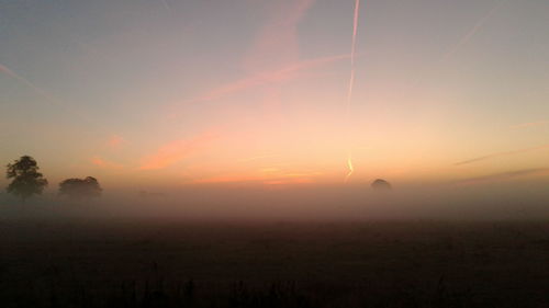 Scenic view of silhouette field against sky during sunset