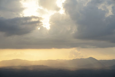 Sunlight streaming through clouds in sky during sunset