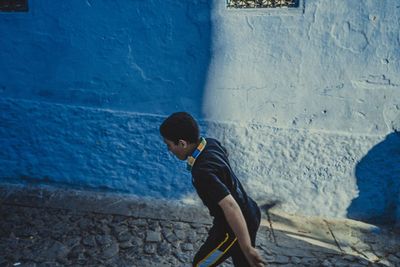 Side view of boy standing against wall