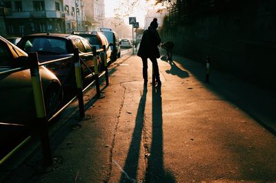 Rear view of silhouette man on car in city