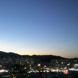 Illuminated cityscape against clear sky at night