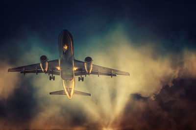 Low angle view of airplane flying against sky at sunset