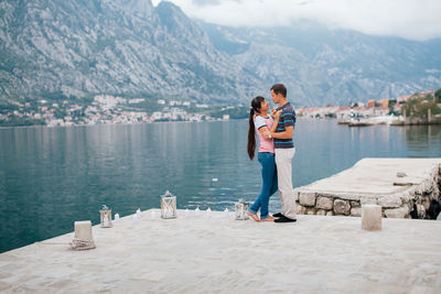 Couple standing at lake against mountains