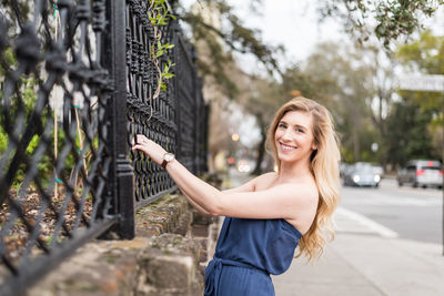 Portrait of smiling young woman holding fence