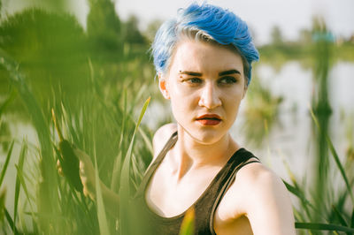 Close-up of young woman holding cattail while standing on field