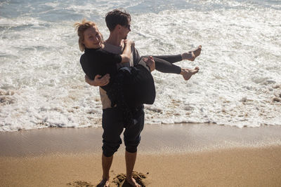 Full length of friends on shore at beach