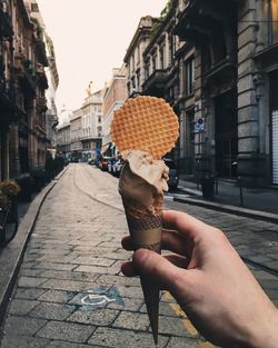 Man holding ice cream cone on street in city