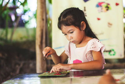 Cute girl looking at camera while sitting on table