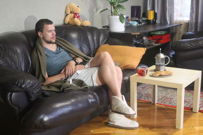 Young man sitting on sofa at home