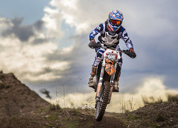 Man riding motorcycle on field against sky
