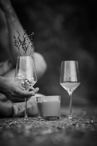 Black and white photo to a candle between 2 wine glasses and a hand