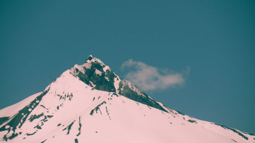 Low angle view of snowcapped mountain against blue sky