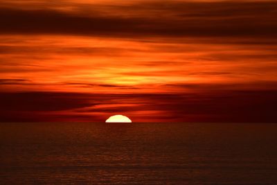 Scenic view of sea against dramatic sky during sunset