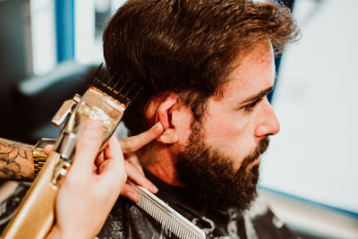 Cropped hands of barber grooming customer in salon