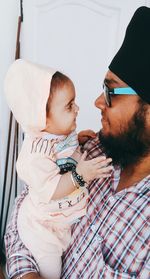 Father carrying baby while standing against door