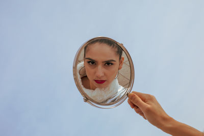 Cropped hand of woman holding mirror in city