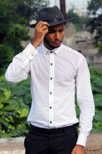 Young man looking away while standing outdoors