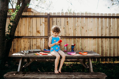 Young girl sitting alone on picnic table eating watermelon