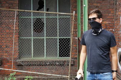 Man wearing sunglasses while holding distress flare against brick wall