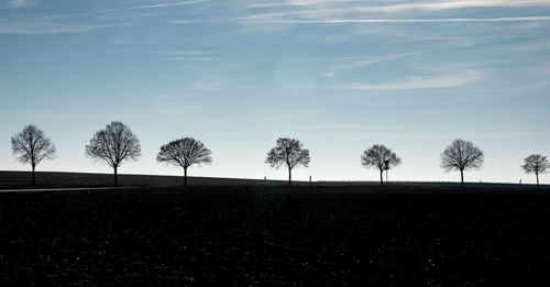 Silhouette trees on field against sky