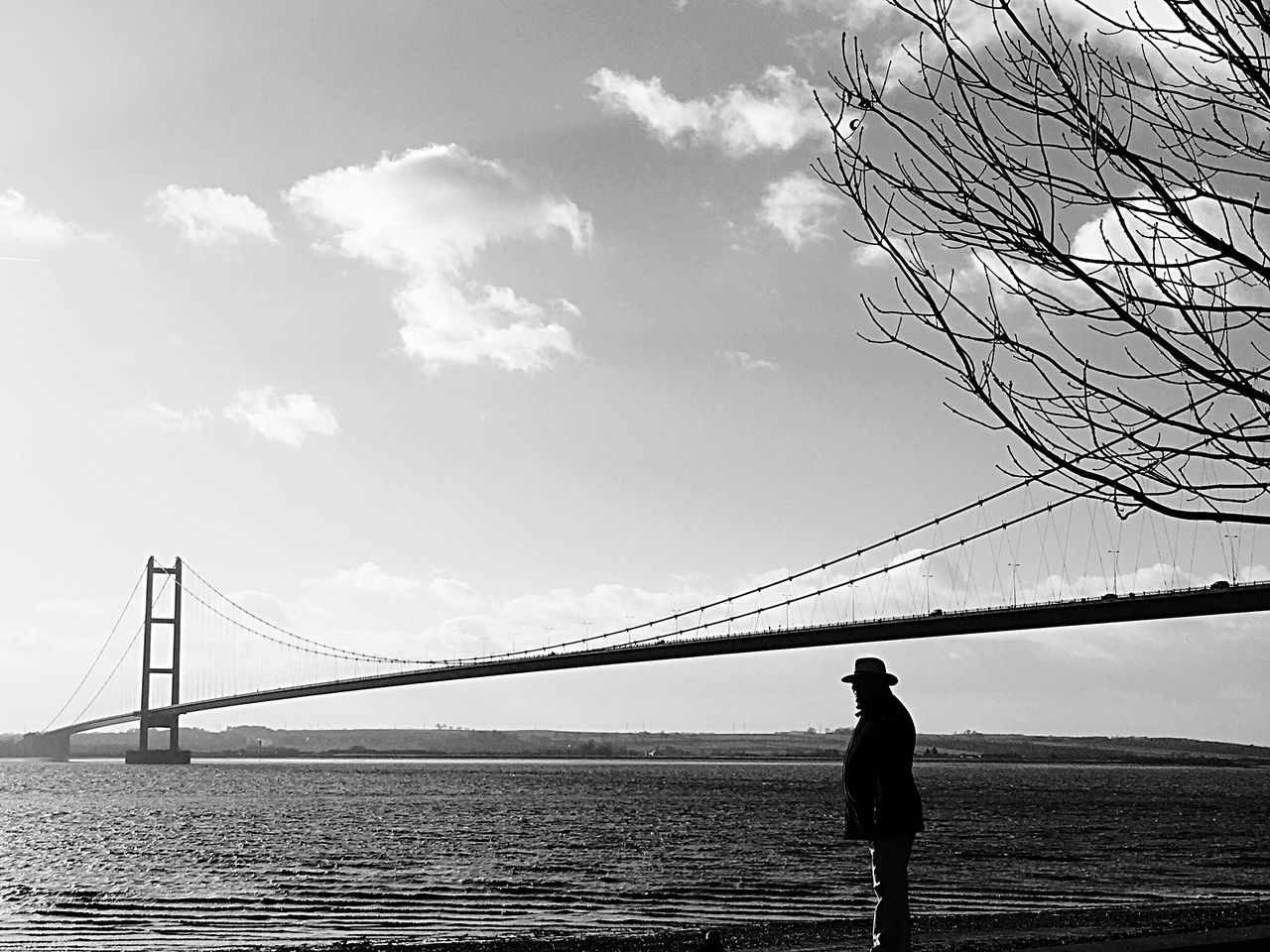 MAN LOOKING AT SUSPENSION BRIDGE AGAINST SKY