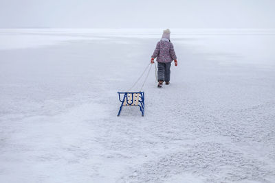 Rear view of woman walking on snow covered land