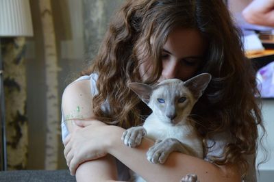 Close-up of young woman hugging cat