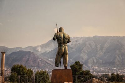 Statue of buddha against mountain range against sky