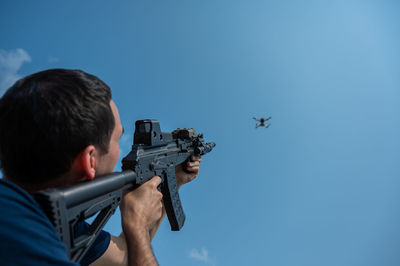 Low angle view of man standing against clear blue sky