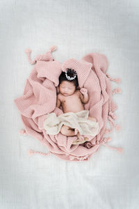 Portrait of cute baby girl lying on pink background