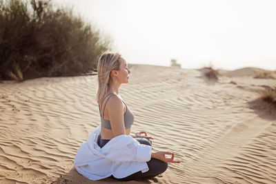 Full length of woman sitting in the desert