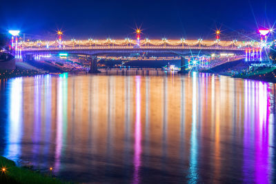 Illuminated bridge over river at night