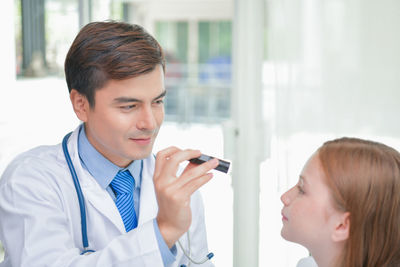 Male doctor examining girl in hospital ward