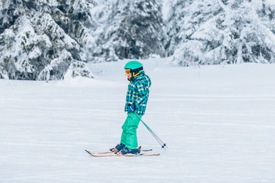 Full length of boy skiing against snow covered trees