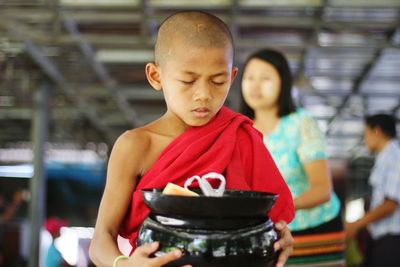 Close-up of monk holding bowls in temple