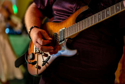 Midsection of man playing guitar